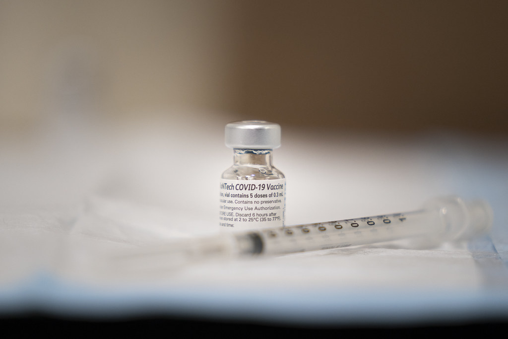 A vial labeled "COVID-19 Vaccine" with a syringe